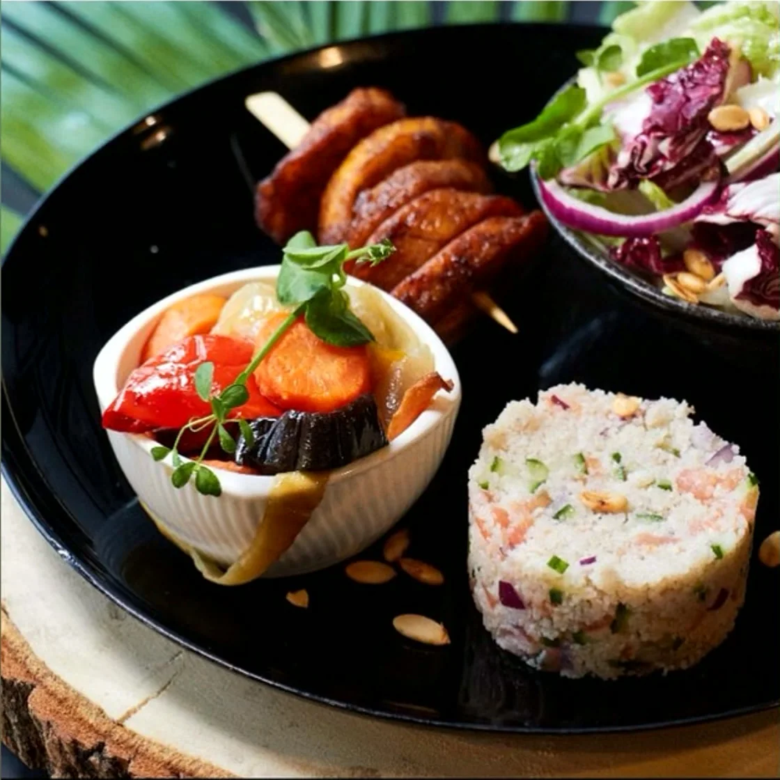 Assiette composée : brochettes, riz et salade sur un plateau sombre